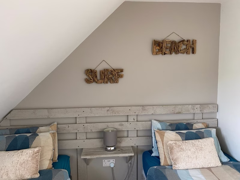 Sea Dream Lodge — twin bedroom with coastal BEACH sign décor
